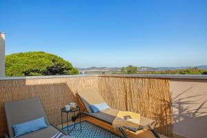 ein Balkon mit zwei Stühlen und einem Tisch in der Unterkunft Piscine & Soleil à Hyères - T3 spacieux avec Clim & Extérieurs in Hyères