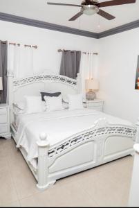 Una cama blanca en un dormitorio blanco con techo. en hermosa casa en las orquídeas la romana, en La Romana