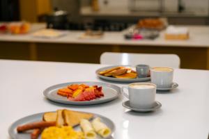 una mesa con platos de comida y dos tazas de café en Indie Universe Creative Hotel, en Medellín