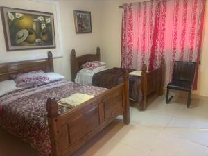 a bedroom with two beds and a chair at Hostal Familiar Casa de Quincha in Las Tablas