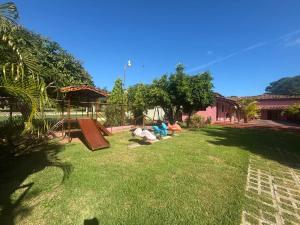 a yard with a playground with people laying on the grass at Hostal Familiar Casa de Quincha in Las Tablas