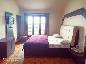 a bedroom with a large bed and a large window at Krishna residency in Ooty +5 photos