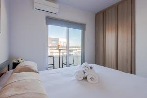 a bedroom with a white bed with towels on it at TelMar Sky View in Larnaca