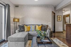 a living room with a gray couch and yellow pillows at Amazing Views 1BR Condo with Hot Tub and Pool in Canmore