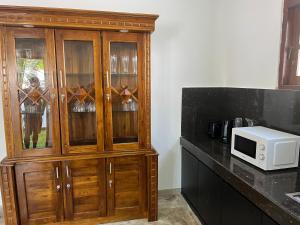 a wooden cabinet in a kitchen with a microwave at Villa J-95 in Galle