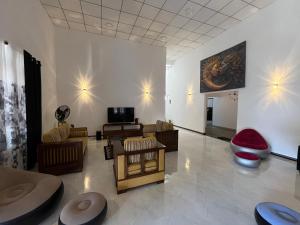 a living room with couches and chairs and a painting on the wall at Villa J-95 in Galle