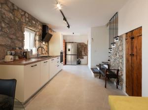 a kitchen with white cabinets and a stone wall at Ana Stone House Jurcic Kalic in Vranjak