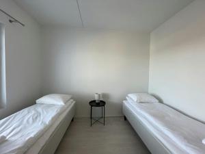 two beds in a room with a side table at Central Apartment for 4 with Sauna in Seinäjoki