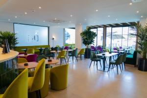 a restaurant with tables and chairs and a large screen at Lake & More Suite Hotel in Paratico