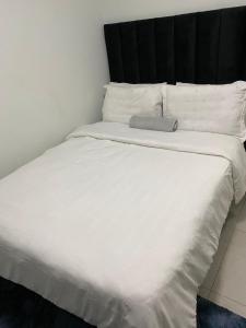ハボローネにあるKhumoetsile BnBの黒いヘッドボードと白い枕が付いた白いベッド