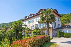 a large building with palm trees in front of it at Villa Anna Isole Borromee in Baveno