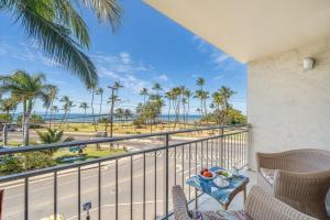 a balcony with a view of the beach and palm trees at Island Surf 306 · ISF 306 1BD w Ocean Views AC Pool Near Beach in Kihei