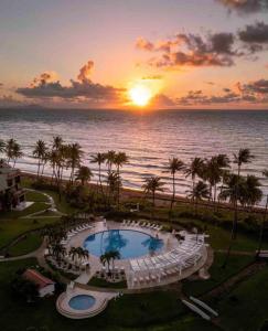 a sunset over the ocean with a pool and chairs at Selah in Palmas del Mar in Buena Vista