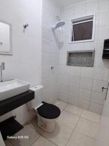 a white bathroom with a toilet and a sink at Casa de férias Pôr do Sol 2 in Presidente Epitácio