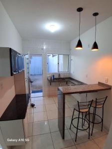 a kitchen with a counter and two bar stools at Casa de férias Pôr do Sol 2 in Presidente Epitácio +23 photos