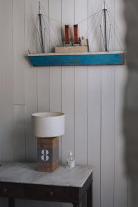 a table with a lamp and two model boats on a wall at L'Olivier de Milou in Le Bois-Plage-en-Ré