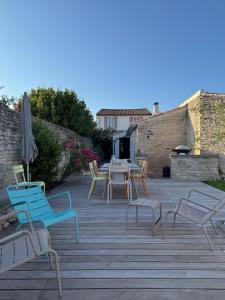 a patio with chairs and a table and an umbrella at L'Olivier de Milou in Le Bois-Plage-en-Ré