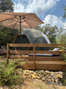 a yurt with an umbrella on a wooden deck at Spa Les Jardins De Chiron Lodges et Tiny House dans le sud in Sauve