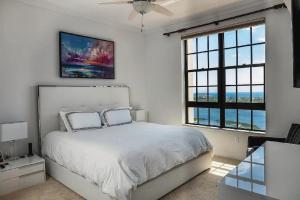 a white bedroom with a bed and two windows at Elegant 2 Bedroom Condo with Ocean Views in West Palm Beach +25 photos
