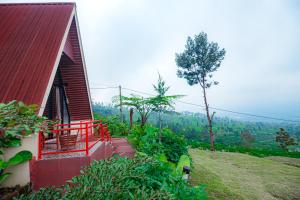 a small house with a red balcony on a hill at Khanzana Cabin and Camp in Kejajar