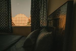 a bedroom with a bed and a window with a building at Jai Kutir Homestay - Hawa Mahal View in Jaipur