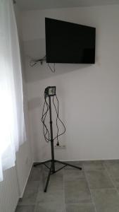 a flat screen tv on a white wall with a tripod at Opatment - die Nussschale in Mörbisch am See