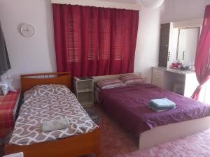 two beds in a bedroom with red curtains at Vasilis House family room in Larnaka