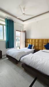 a bedroom with two beds and a green curtain at Hotel Yoga Stay Rishikesh in Rishīkesh