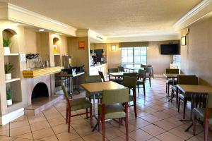 a restaurant with tables and chairs and a fireplace at Townhouse Garden Inn & Suites San Antonio I 35 in San Antonio