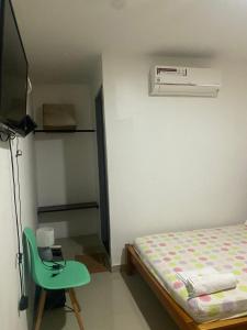 een kleine slaapkamer met een bed en een groene stoel bij Hotel Boutique 51 in Barrancabermeja