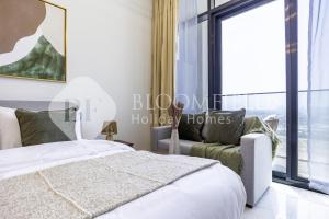 Un dormitorio con una cama y un sofá y una ventana. en Bloomfields EcoGate Stu Masdar City, en Abu Dhabi Intl