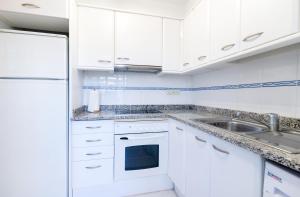 a white kitchen with white cabinets and a sink at Apartaments Ancora in Palamós