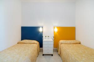 a bedroom with two beds and a yellow wall at Apartaments Ancora in Palamós