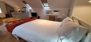 Un dormitorio con una gran cama blanca y una cocina. en The Coach House Studio Apartment, en Leamington Spa