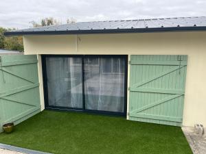 a garage with green doors and green grass at bulles et détente in Seuil