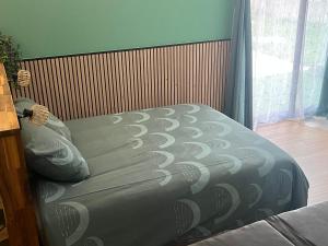 a bed with a gray comforter in a bedroom at bulles et détente in Seuil