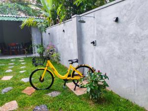 uma bicicleta amarela estacionada na grama ao lado de um muro em Amarante Madiha em Matara