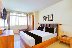 a bedroom with a large bed and a desk at Hotel O Indian Suites in Bengaluru