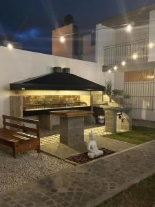 サンタ・テレシータにあるLo de Carlosの石のグリルとベンチのあるパティオ