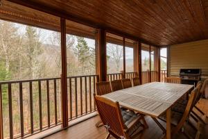 a large screened in porch with a wooden table and chairs at Deluxe Ski in-out - HotTub - Fire - PingPong - View in Mont-Tremblant