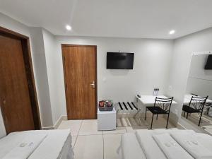 ein Schlafzimmer mit Bett, Tisch und Fernseher in der Unterkunft HOTEL POLASTRELLI in Governador Valadares
