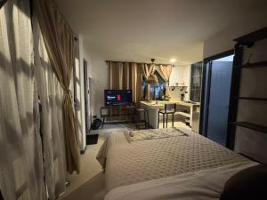 a bedroom with a bed and a desk and a kitchen at La Aldea in Mocoa