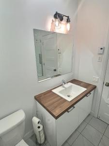 a bathroom with a sink and a toilet and a mirror at Chez Temporel - Condo urbain in Quebec City
