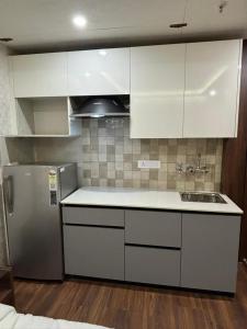 Una cocina con gabinetes blancos y un refrigerador de acero inoxidable. en QuickIn Stayz managed by The AIKaya Hotels, en Gurgaon