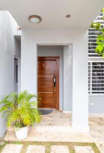 a wooden door in a white house with two plants at Beautiful family home LR in La Romana