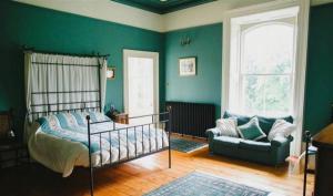 a bedroom with green walls and a bed and a couch at Ballynacree House and Cottages in Balnamore