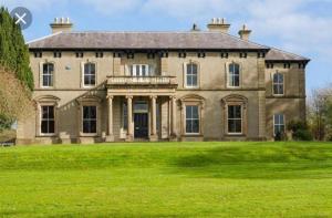 a large brick house with a large grass field at Ballynacree House and Cottages in Balnamore