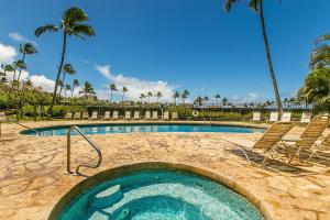 a swimming pool with chairs and palm trees at Regency 620 in Koloa