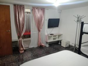 a bedroom with a bed and a tv and curtains at la reyna in Monte Grande +3 photos