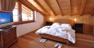 a bedroom with a bed and a television and slippers at Gorgeous Home Saser in Santa Cristina in Val Gardena